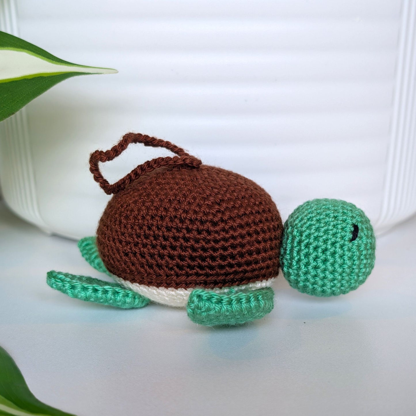 Crocheted jade green body sea turtle with brown shell and a string