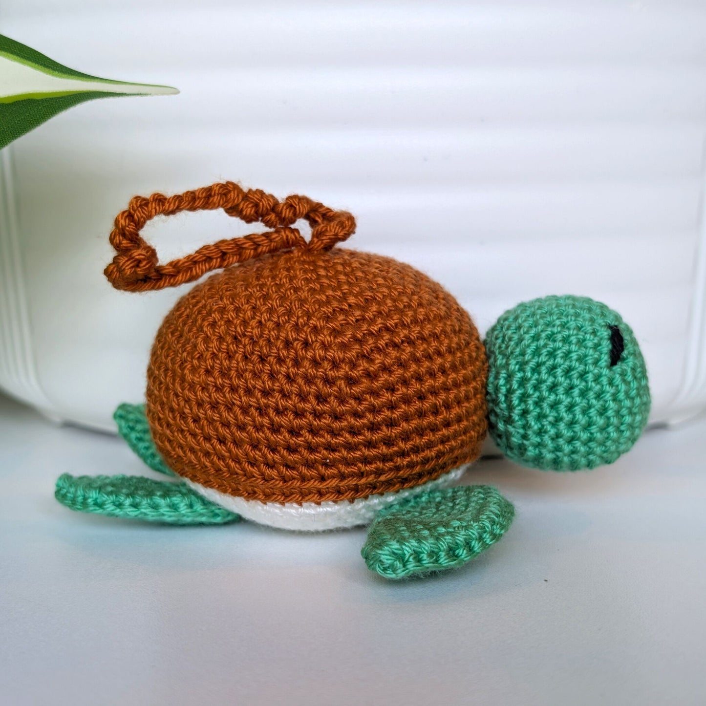Crocheted jade green body sea turtle with ginger shell and a string