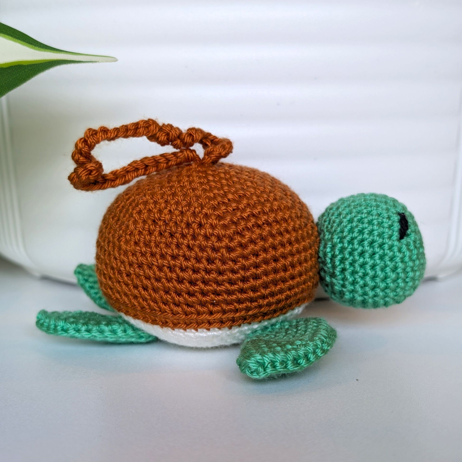 Crocheted jade green body sea turtle with ginger shell and a string