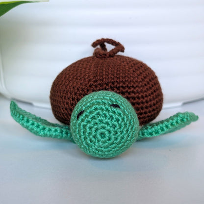 Front view of crocheted jade green body sea turtle with brown shell and a string