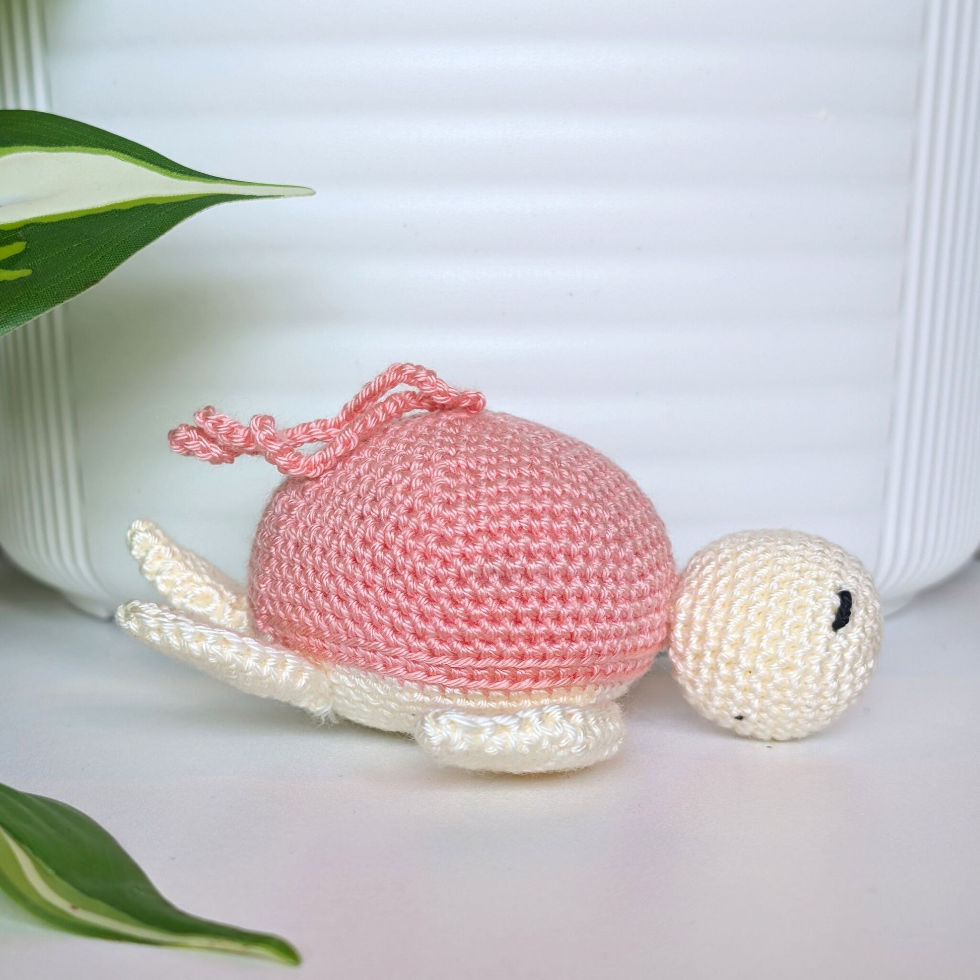 Crocheted sea turtle charm keychain with a coral pink shell