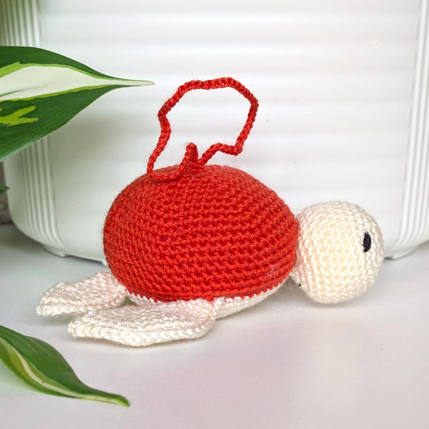 Crocheted sea turtle charm keychain with a red orange shell
