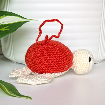 Crocheted sea turtle charm keychain with a red orange shell