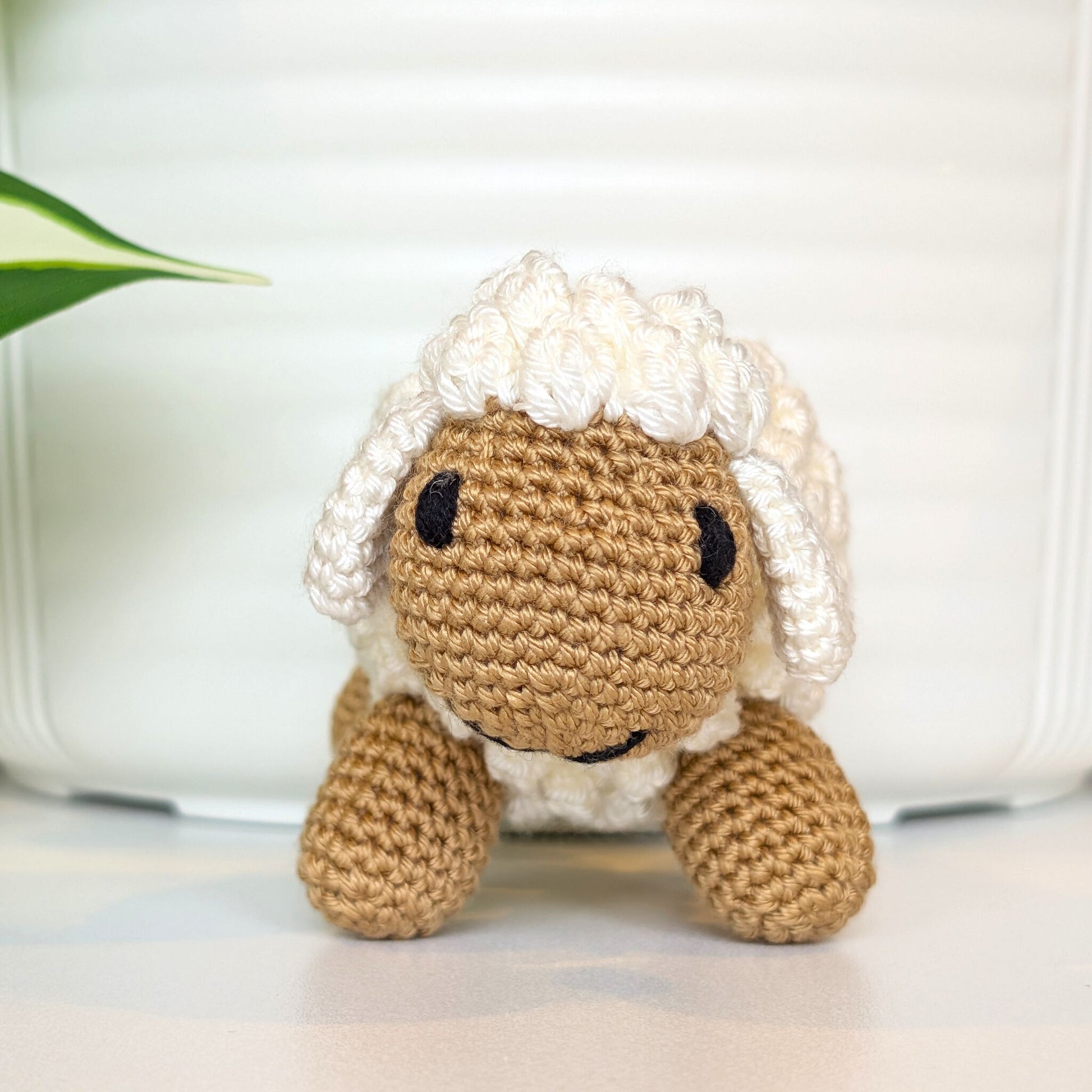 Front view of crocheted cream fleece sheep plush with dark beige body