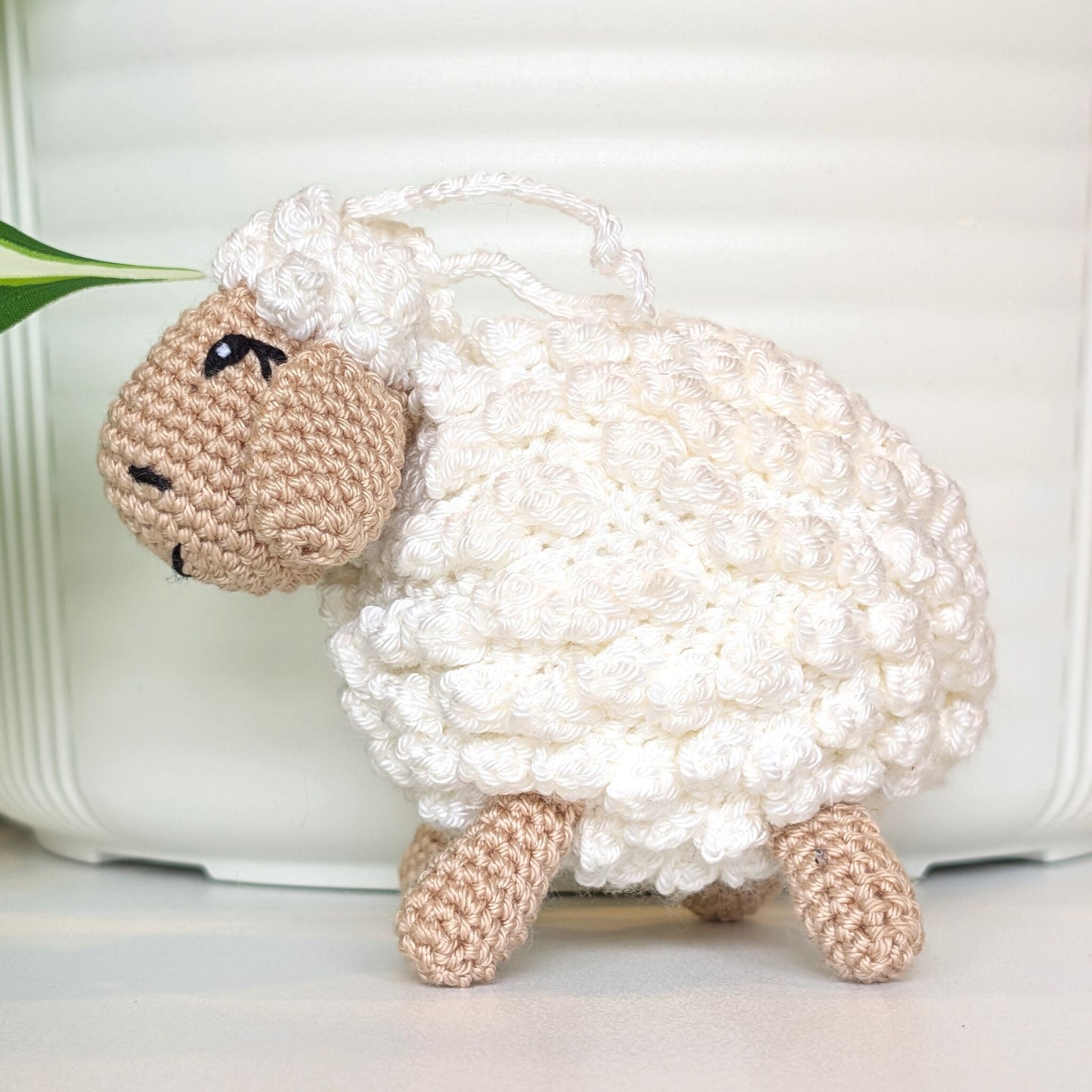 Crocheted sheep plush with beige body with an attached sting