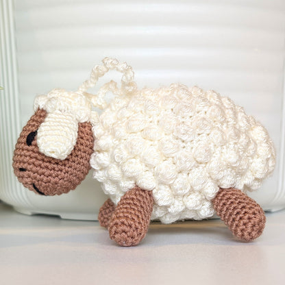 Crocheted sheep plush with oatmeal body with an attached sting