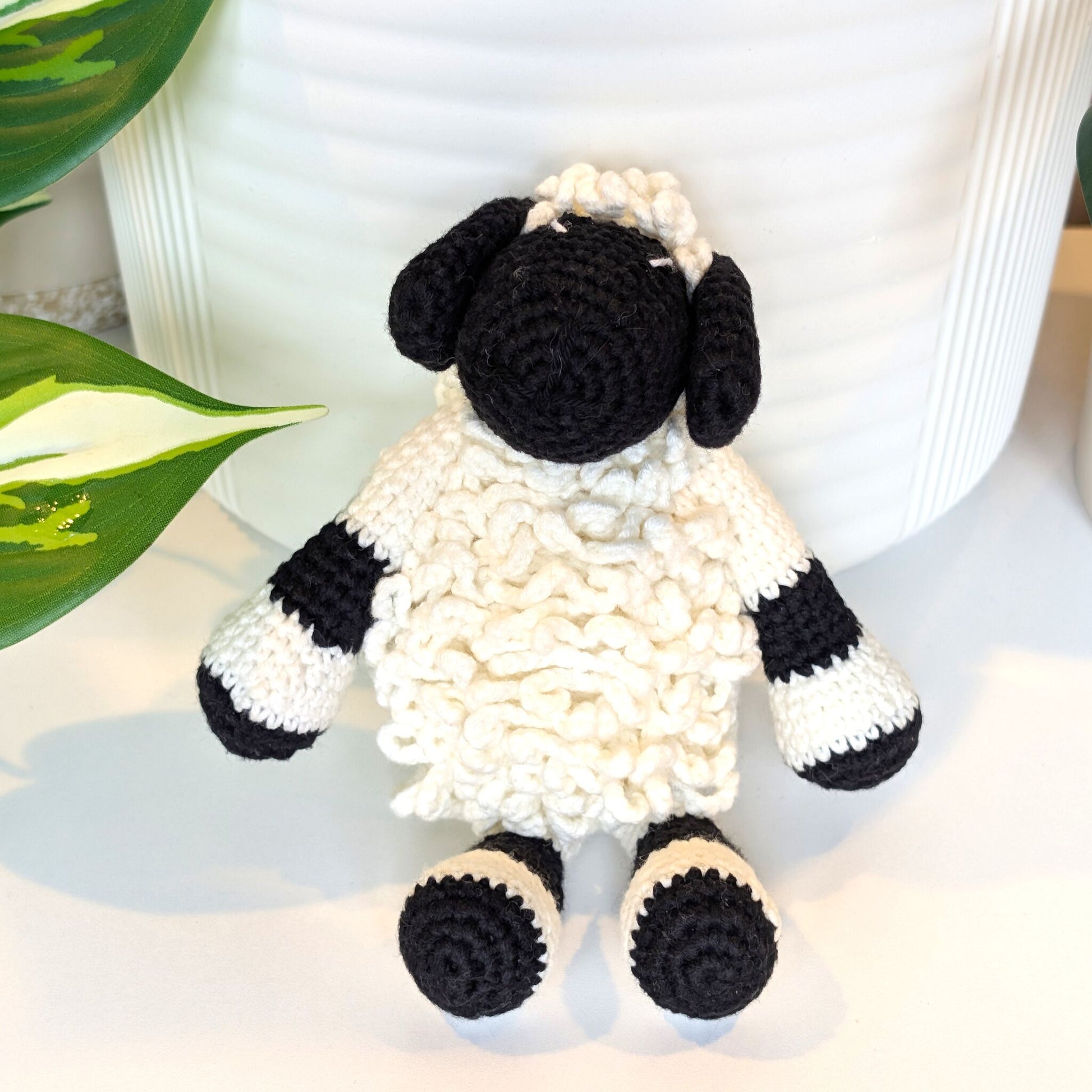 Front view of crocheted sheep toy with black and white pattern on a light background