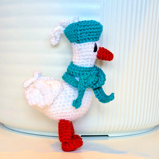 Crocheted duck keychain charm wearing a soft teal beret and scarf, attached to a string