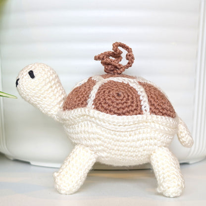 Crocheted turtle charm with a dusty pink shell with white body