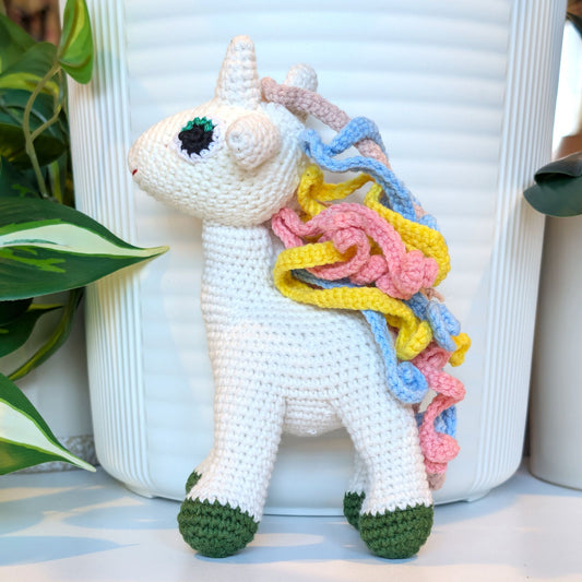 Crocheted plush unicorn toy in colorful mane and forest green feet