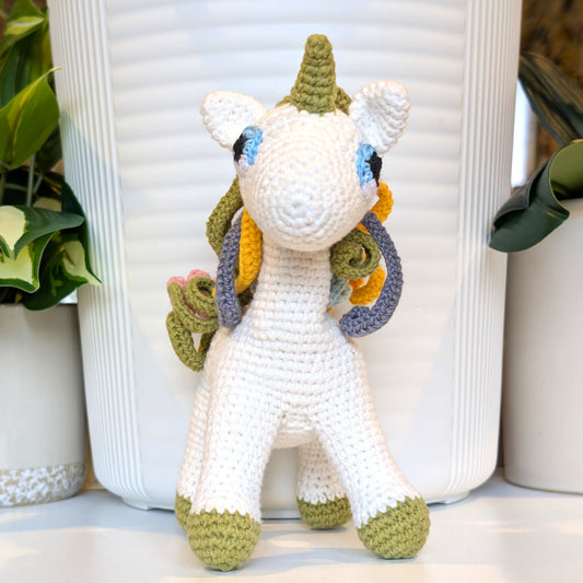 Crocheted unicorn plush with colorful mane and light olive feet