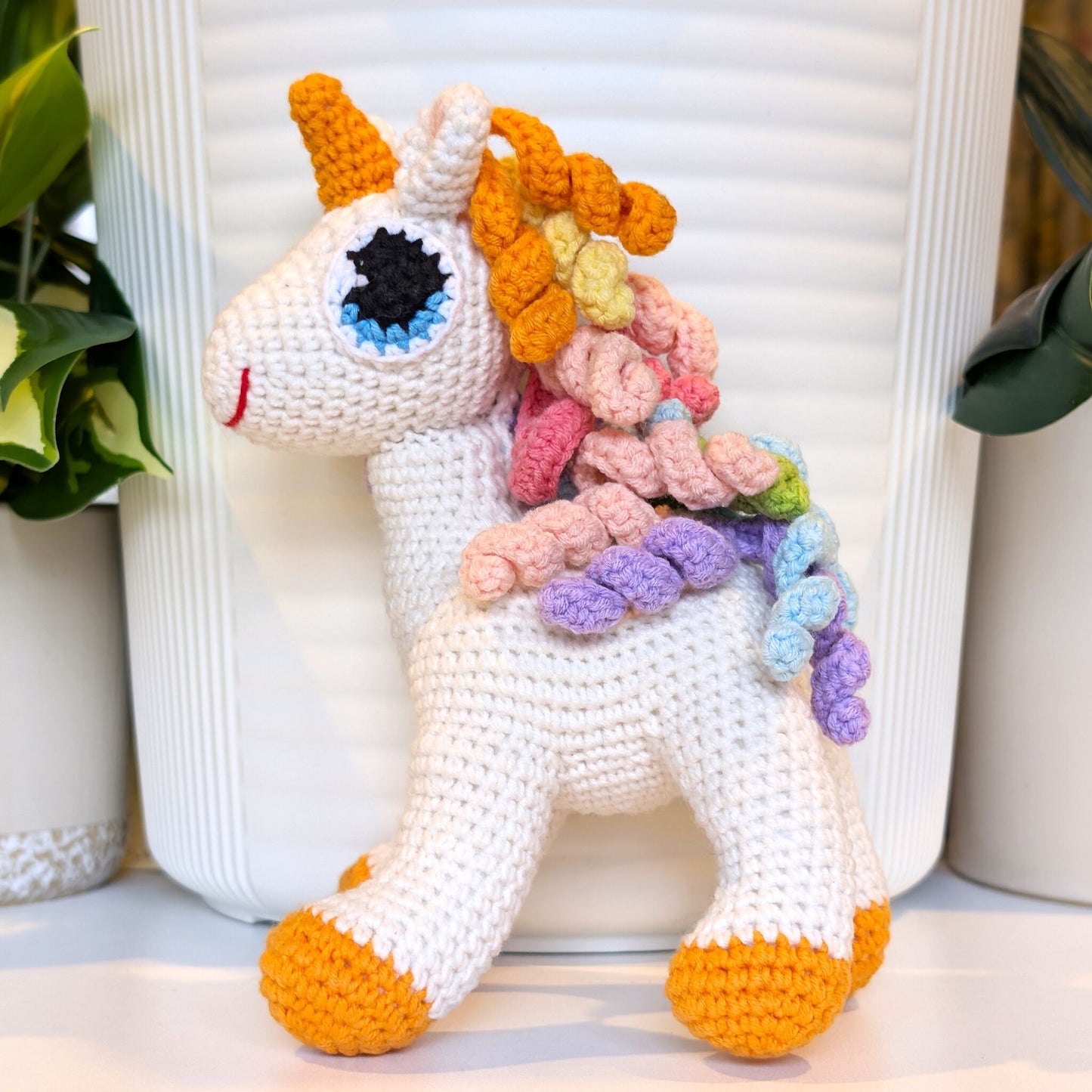 Colorful crochet unicorn plush toy with rainbow mane with orange feet