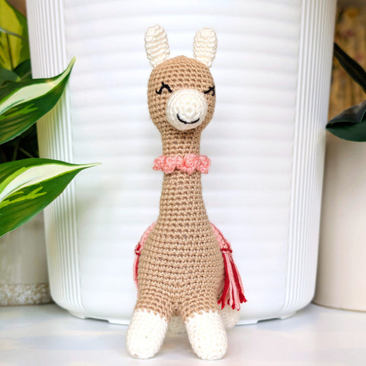 Crocheted Vicuna llama plush with a necklace and pink, red saddle