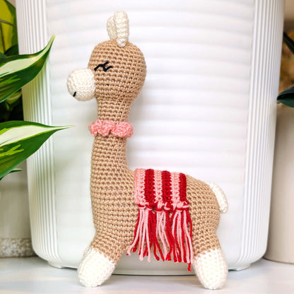 Crocheted Vicuna llama plush with a necklace and pink, red saddle