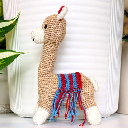 Side profile of crochet Vicuna llama with a red and azure saddle