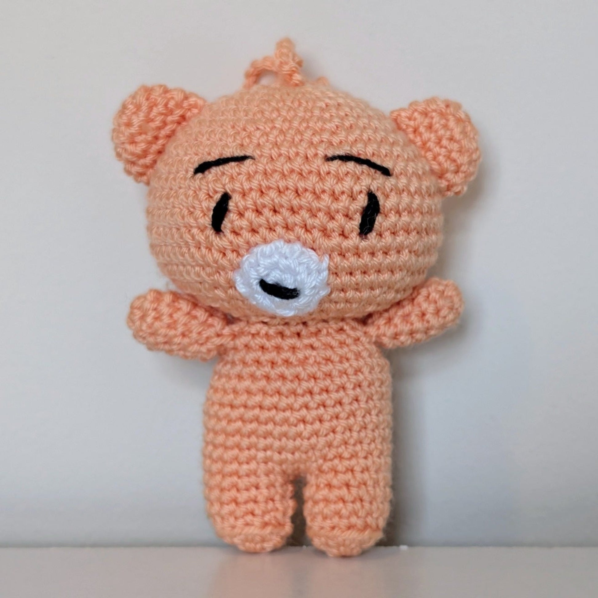 Peach colored crocheted mini teddy bear bag charm with string